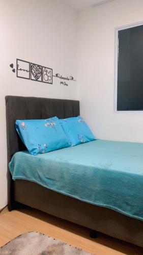 a bed with blue sheets and a flat screen tv at Aconchego da day in Aracaju