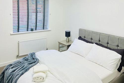 ein Schlafzimmer mit einem Bett mit weißer Bettwäsche und einem Fenster in der Unterkunft 2 Bed House Sleeps 4 - Private Garden Parking in Coventry