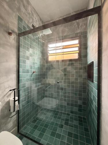 a bathroom with a shower with green tile at Suítes da Sereia in Cananéia