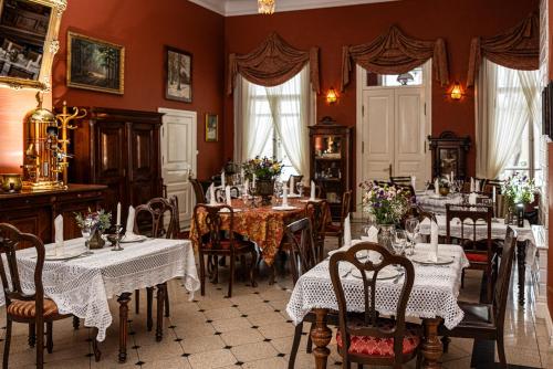 a dining room with tables and chairs and red walls at Apartamenty Carskie in Białowieża