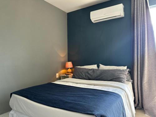 a bedroom with a bed with a blue wall at Hotel Bossa Nova Cabo Frio Passagem flat com varanda in CFB
