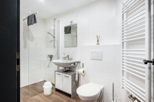 a white bathroom with a toilet and a sink at Haus an der Ache in Fieberbrunn