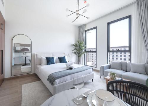 a white bedroom with a bed and a living room at StayShort - Town Square sleeps 2 in Great Location in ‘Ūd al Bayḑāʼ
