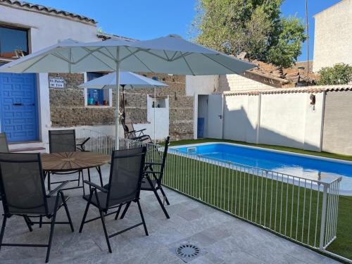a patio with a table and umbrella and a pool at Casa Antonia in La Puebla de Montalbán