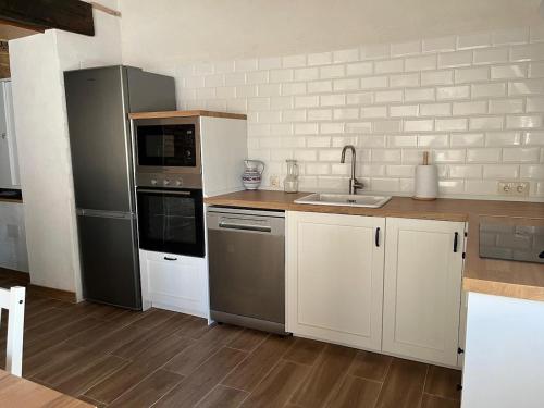 a kitchen with stainless steel appliances and white cabinets at Casa Antonia in La Puebla de Montalbán