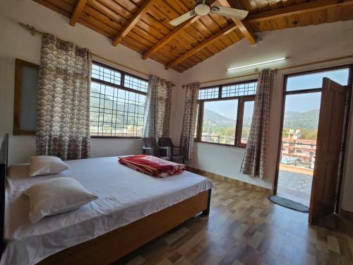 a bedroom with a large bed and large windows at Shree Dev Asthanam in Bhīm Tāl