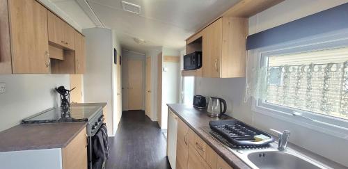 a small kitchen with a sink and a stove at Stunning Holiday Home Beautiful Lakeside Views 15 Mins from Goodwood in Merston