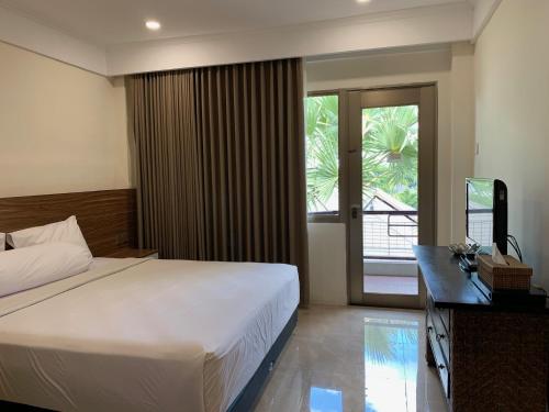een slaapkamer met een bed, een bureau en een televisie bij The Jayakarta Residence 2BR Bali in Denpasar