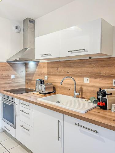 a kitchen with white cabinets and a sink at Puilborin, appartement cosy, avec terrasse in Puilboreau