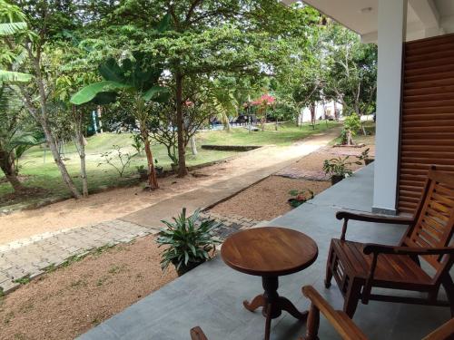 a porch with a wooden table and a chair and a street at Weligama Ocean Breeze in Weligama