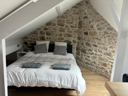 a bed in a room with a stone wall at Petit cocon avec vue sur mer in Dinard