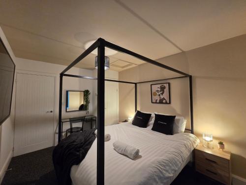 ein Schlafzimmer mit einem Himmelbett mit weißen Laken und schwarzen Kissen in der Unterkunft Modern 5 Bedroom Retreat, With Valley Views, Near Bike Park Wales in Troed-y-rhiw
