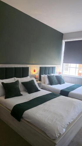 two large beds in a room with a window at The Royal Sutton in Sutton Coldfield