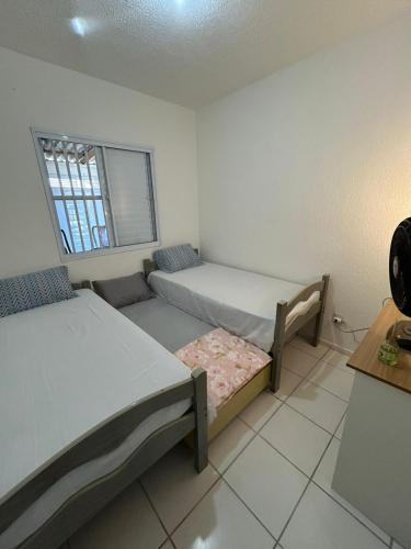 a small room with two beds and a window at Casa Sol & Churrasco in Guarujá