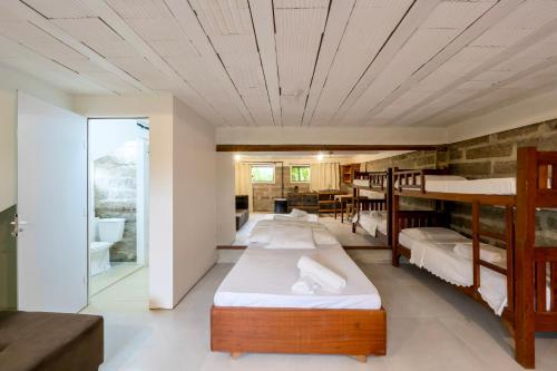 a room with four bunk beds and a bathroom at Sapê Guest Hotel in Praia do Rosa