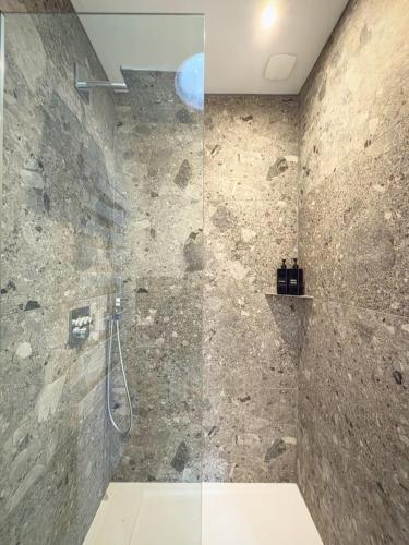 a bathroom with a shower with a stone wall at Petit Albert, confortable, proche de La Rochelle in Aytré