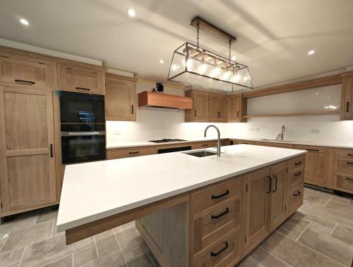 une cuisine avec des armoires en bois et un comptoir blanc dans l'établissement 4 Bed in Snettisham oc-i33650, à Snettisham