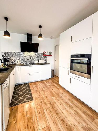 a kitchen with white cabinets and a wooden floor at Le Galet Rochelais in La Rochelle