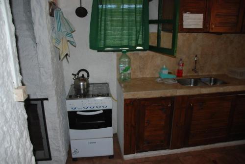 Una pequeña cocina con estufa y fregadero. en Excelente casa de descanso, en Barra de Valizas