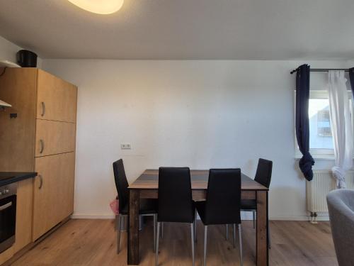 a dining room with a table and black chairs at Mikra Homes24 in Meerane in Meerane