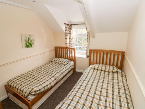 two beds in a room with a window at Swallows Cottage in Walton East