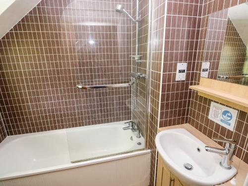 a bathroom with a shower and a tub and a sink at Swallows Cottage in Walton East
