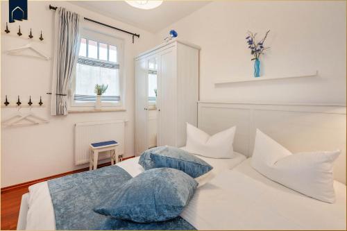 ein Schlafzimmer mit einem weißen Bett mit Kissen und einem Fenster in der Unterkunft Paul-Kühne-Str 4 Tintenfisch in Ostseebad Koserow