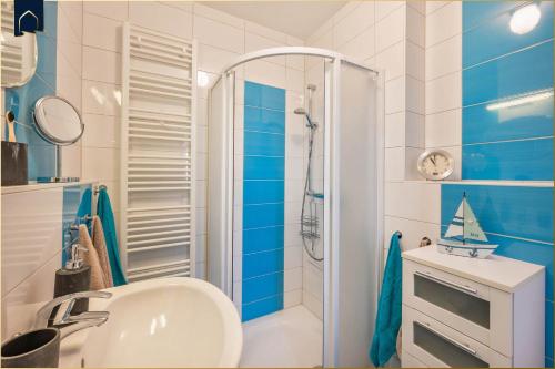 ein blau-weißes Bad mit einem Waschbecken und einer Dusche in der Unterkunft Paul-Kühne-Str 4 Tintenfisch in Ostseebad Koserow