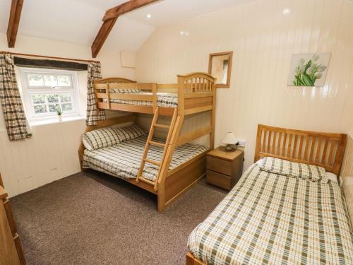 a bedroom with two bunk beds and a window at Rafters Cottage in Walton East