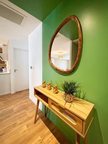 a mirror on a green wall with a wooden table at Joli Perot, Confortable, centre, 5 min du port in La Rochelle