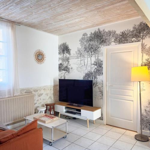 a living room with a flat screen tv on a wall at Maloquet, maison chaleureuse proche Île de Ré in La Rochelle