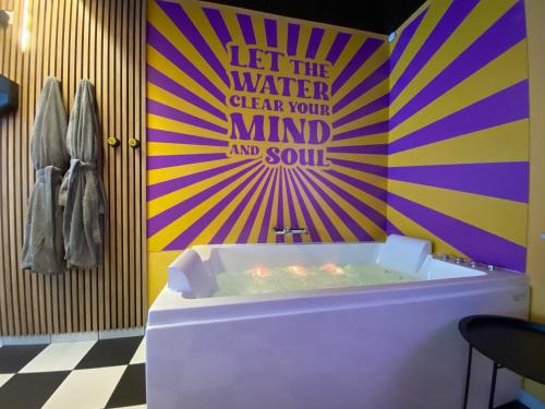 uma casa de banho com banheira e uma parede colorida em Capsule illusion - Balneo - Switch 2 - Mons Centre em Mons