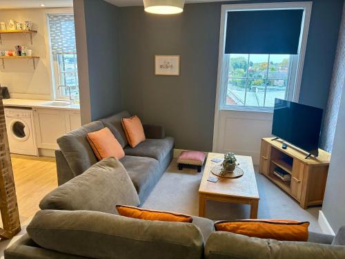 a living room with a couch and a tv at Aspen-free parking-Grade II listed-second floor two bedrooms apartment in Huntingdon