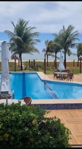 a large swimming pool with palm trees in the background at Itacimirim 3 quartos pé na areia in Camaçari