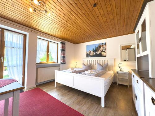 een slaapkamer met een wit bed en een houten plafond bij Landhaus Steibis - Seelekopf in Steibis