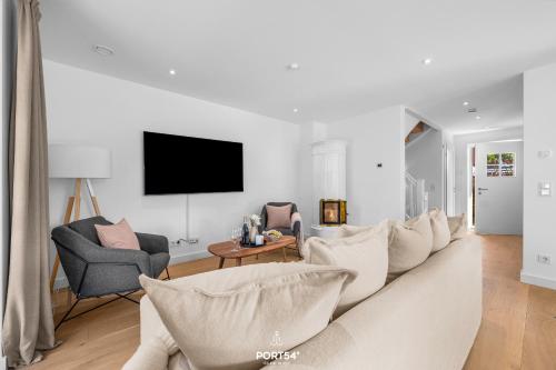 ein weißes Wohnzimmer mit einer Couch und Stühlen in der Unterkunft Villa Tinnum Sylt in Tinnum