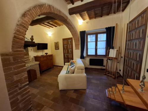 a living room with a white couch and an archway at Il Pacchiarotto - Inside the Medieval Walls & Wi-Fi in Casole dʼElsa