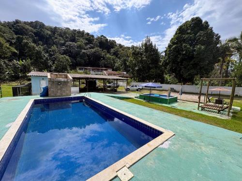 a large swimming pool in front of a house at Rancho Ohana in Peruíbe