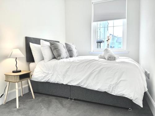 a white bedroom with a large bed and a window at Picturesque Tornagrain Apartment 2bed Free Parking WiFi - Near Inverness Airport 