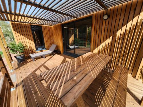a wooden patio with a wooden bench on a deck at Gîte Le rossignol des murailles in Le Bosc