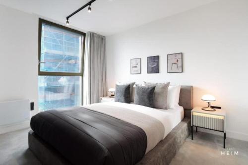 a bedroom with a large bed and a large window at Urbano at The Heim Residences in Manchester