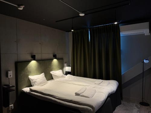 une chambre avec un grand lit avec des draps et des oreillers blancs dans l'établissement Playhotel, à Mjölby
