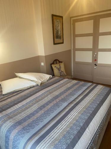 a bed with a blue and white striped bedspread at cocon beaujolais in Anse