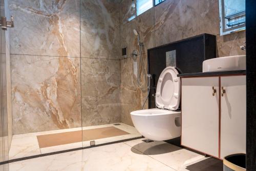 une salle de bain avec toilettes et douche en verre dans l'établissement Hotel Golden Amulya Rest Wings, à Yelahanka