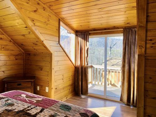 a bedroom with a large window in a log cabin at Oak Tree cabin near the Shenandoah River in Oak Hill