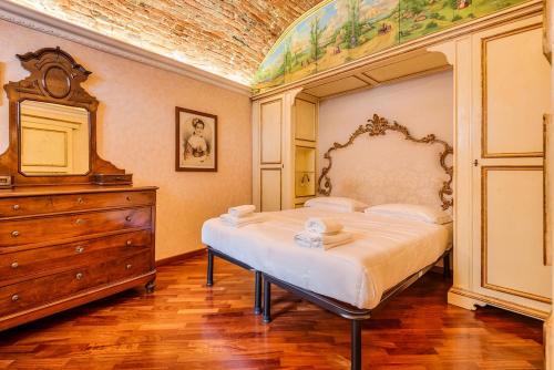 a bedroom with a large bed and a dresser at Affreschi and Vintage Charm in Bergamo