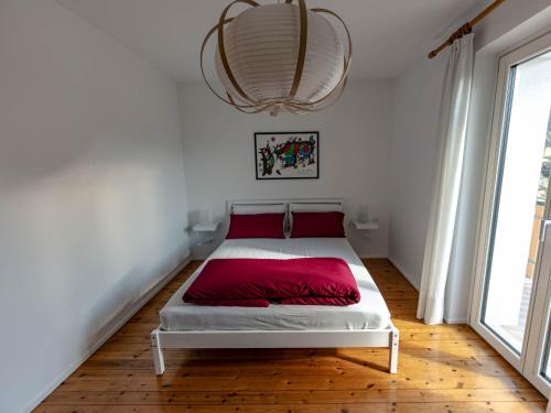 a bedroom with a bed with red sheets and a chandelier at Symphony Home in Pergine Valsugana