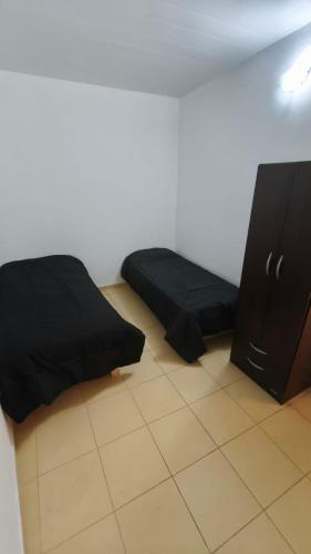 una habitación con una cama negra y un armario en Lavalle dpto 3, en Santiago del Estero