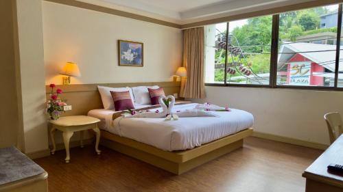 a bedroom with a large bed and a window at Neptuna Kata Beach in Kata Beach