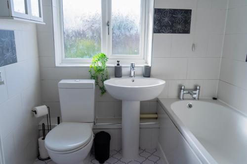 a bathroom with a toilet and a sink and a bath tub at Tranquil Walsall Retreat - 4 Bedrooms in Bloxwich